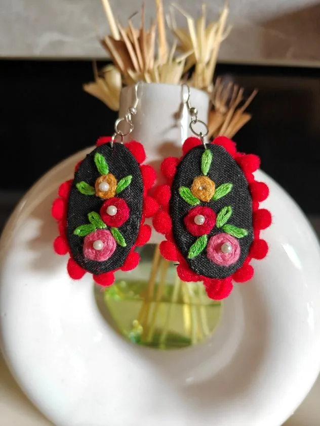 Embroidered fabric earrings with red pom-pom trim